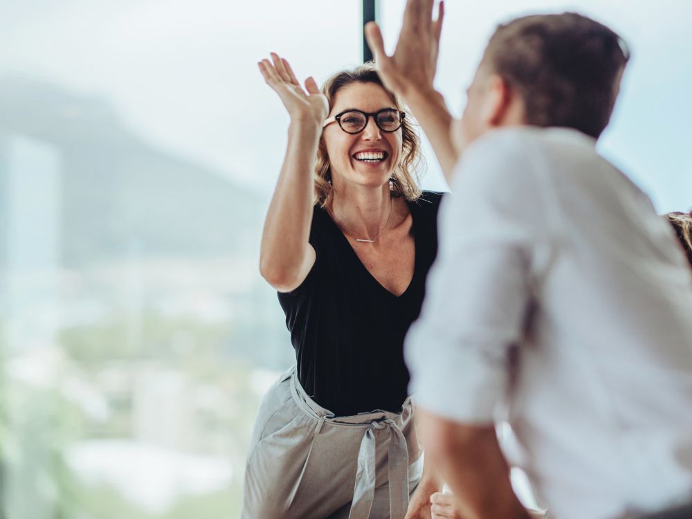 Businesswoman giving a high five to a colleague in a meeting.